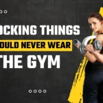 5 Gym Outfit Mistakes That Instantly Ruin Your Workout Fitness graphic showing a muscular man and woman with dumbbells against a black and yellow background, overlaid with the text: "5 SHOCKING THINGS YOU SHOULD NEVER WEAR TO THE GYM."